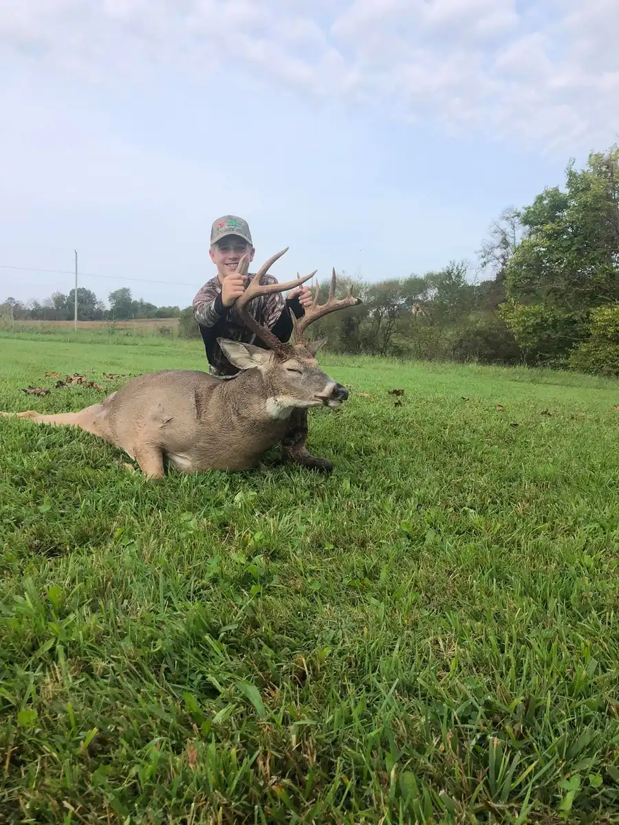 Young hunter proudly displays a large buck with velvet antlers raised.